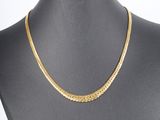 a gold chain necklace on a mannequin torso