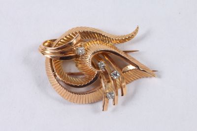 une broche en or sertie de diamants, posée sur un fond blanc