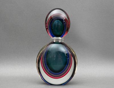 une image représentant un flacon de parfum en verre orné d'un motif multicolore