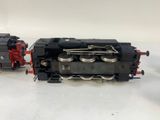 two black and red trains sitting side by side on a white surface