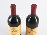 two bottles of red wine sitting next to each other on a white surface