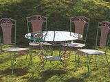 a glass table and four chairs in the grass