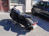 une moto noire garée sur un parking à côté d'une voiture bleue
