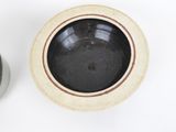 a black and white bowl next to a brown and white bowl