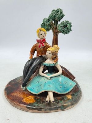 une figurine représentant un homme et une femme assis sur un rocher