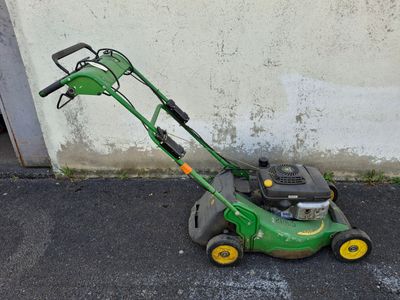 a green lawn mower that is sitting on the ground