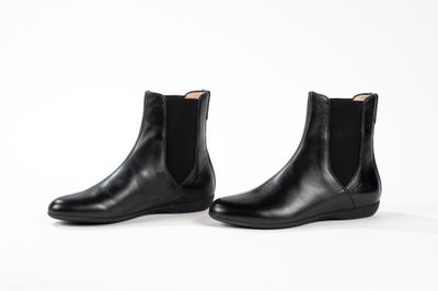une paire de bottines Chelsea en cuir noir sur fond blanc