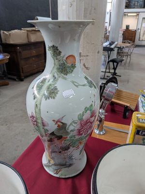 un grand vase posé sur une table sur laquelle se trouvent des assiettes