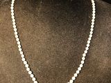 a white pearl necklace on a mannequin with a black background