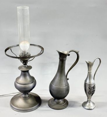 three silver vases and a lamp on a table