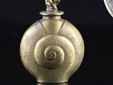a small gold object on a black surface next to a coin
