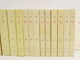 several books are lined up in a row on a white surface