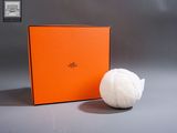 une boîte orange à côté de laquelle se trouve une balle blanche, posée sur une table