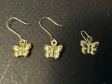 a pair of gold butterfly earrings on a black surface