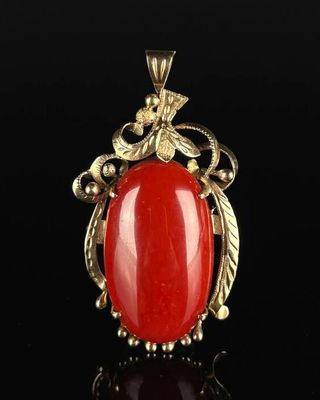 a gold and red stone pendant on a black background