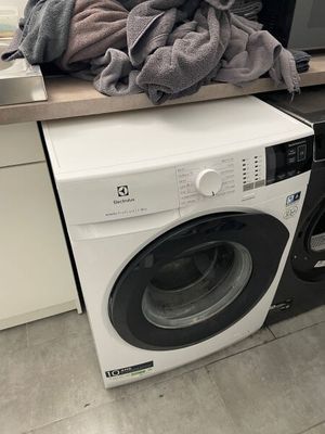 a stack of clothes on top of a washer in a kitchen
