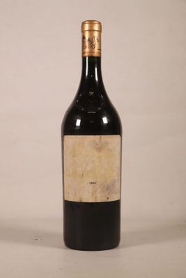 une vieille bouteille de vin posée sur une table blanche