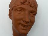 a clay sculpture of a woman ' s face on the wall