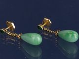 une paire de boucles d'oreilles en or et en jade vert sur un fond noir