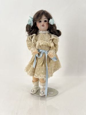 une poupée qui porte une robe et tient un ruban bleu