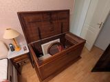un coffre en bois contenant un disque, posé à côté d'un lit
