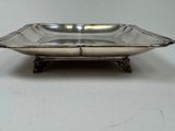 a silver plate on a stand on a white surface