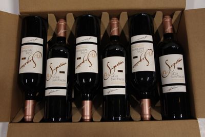 six bottles of wine in a cardboard box on a table