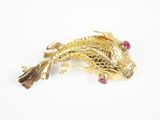 broche en forme de poisson en or jaune avec des yeux en rubis sur fond blanc