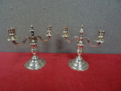 une paire de chandeliers plaqués argent posés sur une nappe rouge
