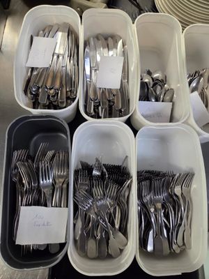 beaucoup de fourchettes et de cuillères dans des récipients posés sur la table