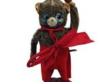 un ours en peluche qui porte un pantalon rouge et une écharpe rouge