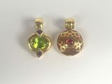 two gold pendants with green and red stones on a white surface