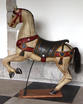 un cheval de bois posé sur un sol à damier noir et blanc