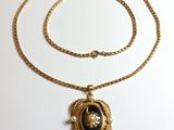 un collier en or avec un pendentif noir et blanc suspendu à une chaîne en or