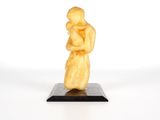 sculpture représentant une femme tenant un enfant dans ses bras, posée sur un socle noir