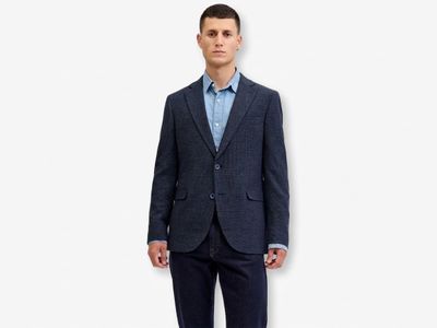 a man in a suit standing against a white wall