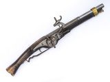 un vieux pistolet avec une poignée en bois sur une surface blanche