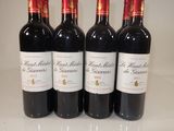 four bottles of red wine are lined up on a table