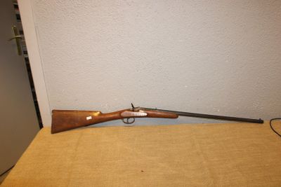 Le fusil est posé sur la table, près du mur.