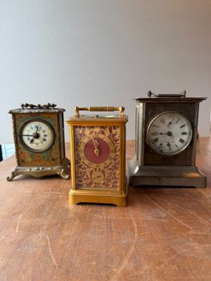 three small clocks sitting on a table next to each other