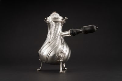 une cafetière ancienne en argent avec une anse, sur fond noir