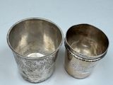 pair of silver cups on a white surface