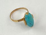 bague en or sertie d'une turquoise sur un fond blanc