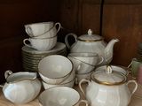 de nombreuses tasses et soucoupes sur une étagère de la cuisine