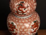 a red and white vase sitting on top of a wooden table
