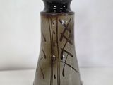 un vase noir et marron posé sur une table blanche