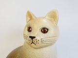 a ceramic cat with brown eyes sitting on a table
