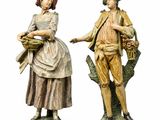 deux figurines représentant un homme et une femme avec des paniers de fleurs