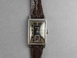 a close up of a watch with a brown strap on a gray surface