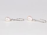 une paire de boucles d'oreilles en perles blanches avec des crochets en argent, sur un fond blanc